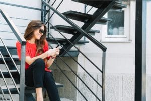 smiling young woman sitting staircase using cellphone 23 2147925320